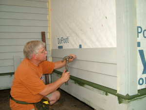 Installing wood siding takes time and is not hard to do. Note the painted ends of the pieces behind my head. Each end is painted before the siding is nailed to the wall. PHOTO BY: Kathy Carter