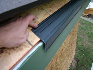 This critical drip-edge flashing is one of the first things that gets installed on top of the slanted wood roof sheathing. It is nailed directly to the bottom of the sloped roof and the roofing felt paper lays down on top of it. Note how the gutter board is already installed, painted and there is a slight gap between the flashing and the gutter board. PHOTO CREDIT: Tim Carter