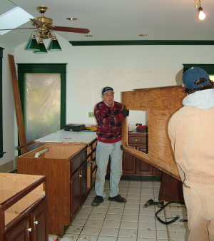 Dennis Eads and Bob Schmidt carry out a worn ceramic tile countertop as my old kitchen is demolished. PHOTO CREDIT: Tim Carter