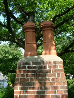 This cement chimney cap is like most. It is lacking an overhang, and it does not have a flashing beneath the cement mortar. PHOTO CREDIT: Tim Carter