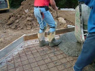 Pouring concrete can be hard work. Each wheelbarrow load can weigh hundreds of pounds. PHOTO CREDIT: Tim Carter