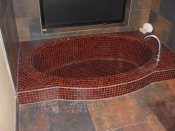 This unique bathroom tub is sunken into the floor and covered with tiny mosaic tile. PHOTO CREDIT:  Tim Carter