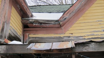 Wood rot is causing the center portion of the house to collapse and pull away from the left section. This is what's causing the giant opening just below the roof overhang.
