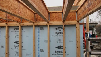 The rigid foam insulation is placed between the stud wall and the foundation wall. Photo Credit: Tim Carter
