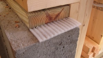 That funny ribbed foam between the wood and the poured concrete foundation is a gasket that prevents air leakage into a home.  Photo Credit: Tim Carter